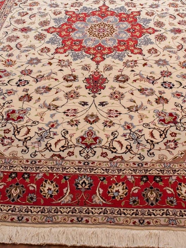 Teppich mit cremefarbenem Feld voller feiner Blütenranken, rotem Medaillon und roter Bordüre mit hellen Fransen